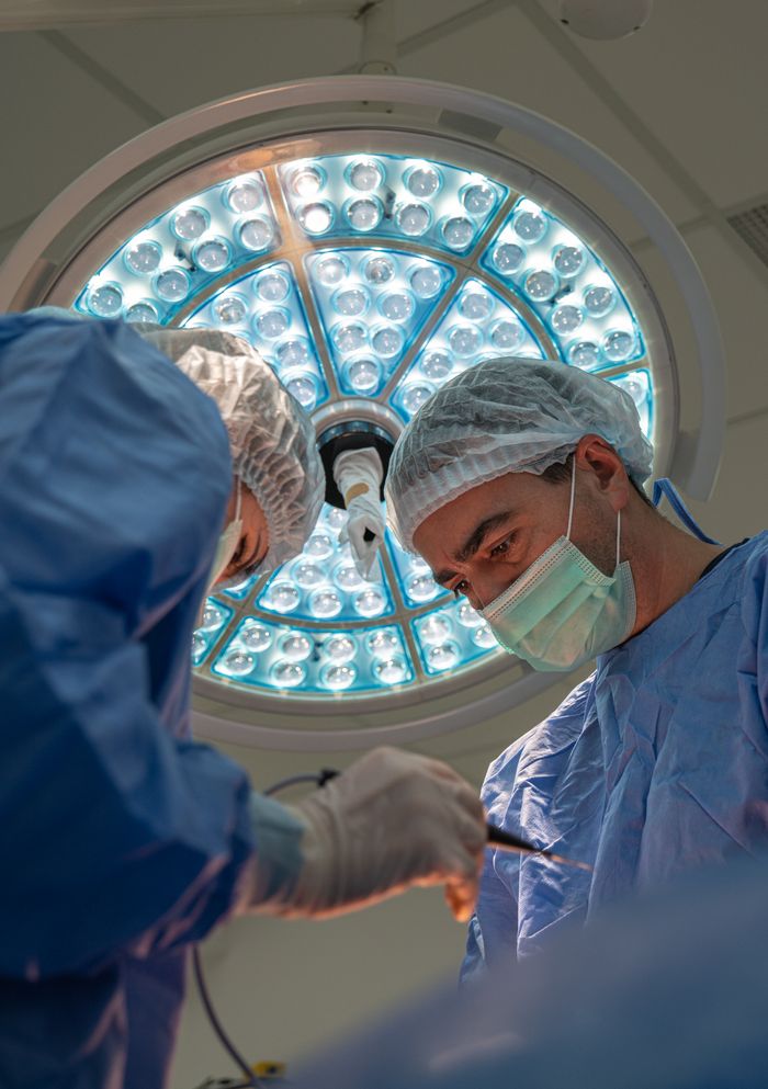 Doctors in surgical attire performing an operation in a well-equipped hospital.
