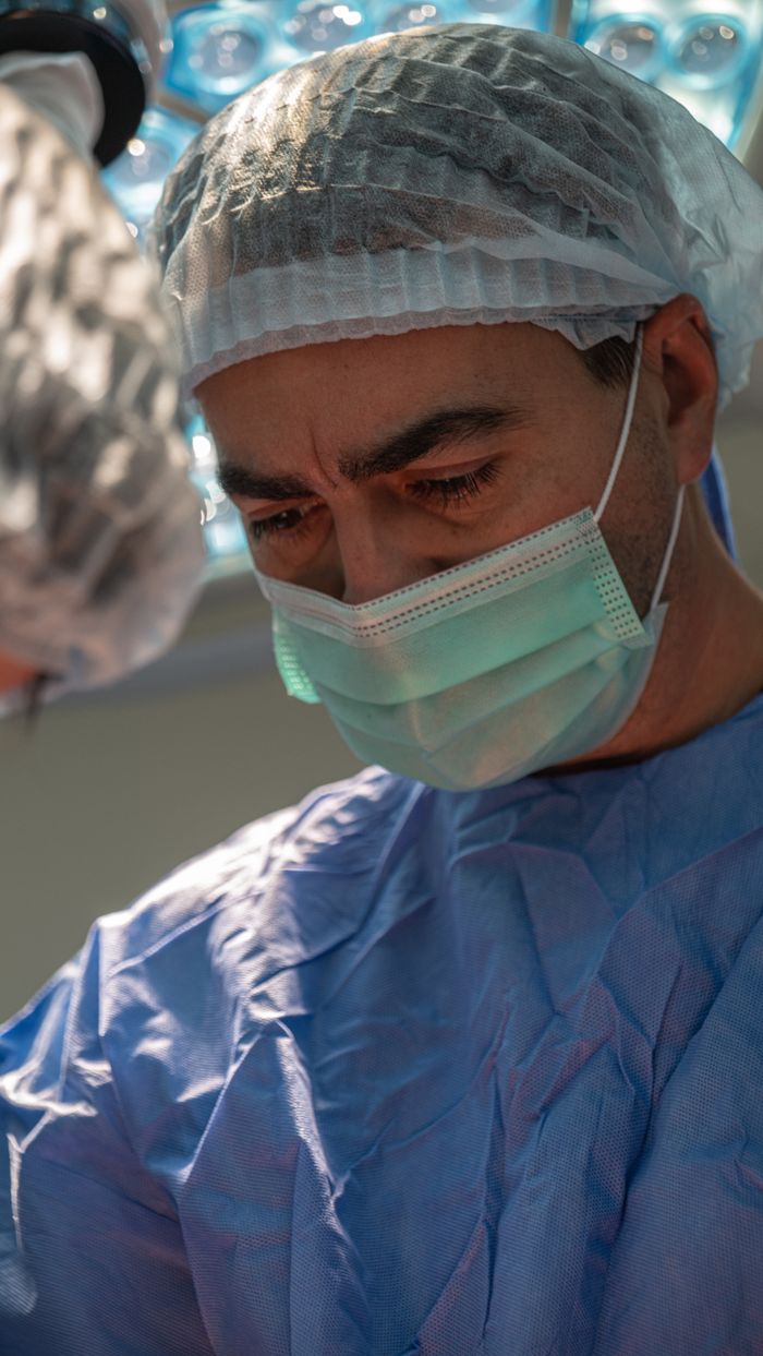Close-up of a focused surgeon wearing a surgical mask and cap during a medical procedure.