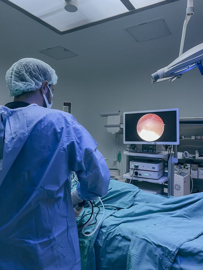 Surgeon in protective clothing performing endoscopic surgery in a hospital operating room.